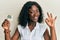 Beautiful african young woman holding paper with aquarius zodiac sign doing ok sign with fingers, smiling friendly gesturing