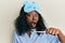 Beautiful african young woman wearing sleeping mask holding toothbrush with toothpaste scared and amazed with open mouth for