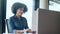 Beautiful afro business woman working and typing with laptop while talking with earphone in coworking place.