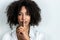 Beautiful afro woman doing gesture of silence with finger with white background