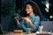 Beautiful afro young business woman taking a photo with her smartphone while eating pasta sitting in the office