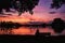 Beautiful afterglow with red clouds over the lake with silhouettes on the shore