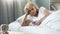 Beautiful aged woman lying in bed, chatting in social networks on smartphone