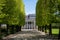 beautiful alley with green trees and historical building with columns and statues