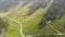 Beautiful alpine valley with layers of mountains and river flowing through it while illuminated partially by sun.