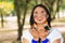 Beautiful Amazonian woman with indigenous facial paint and white traditional dress posing happily for camera in park