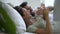 Beautiful American couple is having fun together while lying on bed in white bedroom spbd.