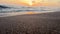 Beautiful anamorphic lense landscape of beach sand and ocean waves rolling on shore at sunset. Peaceful scene of seaside