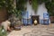 Beautiful Andalusian patio with plants, blue chairs, wooden table and vases placed on a mosaic stone floor. Cordoba, Andalusia,