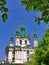 Beautiful Andreevskaya church with turquoise domes decorated with gold, near the flowering chestnuts on the background