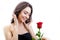 Beautiful angry girl receives one red rose. She is surprised, looking at the flowers and smiling.