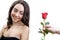 Beautiful angry girl receives one red rose. She is surprised, looking at the flowers and smiling.