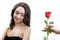 Beautiful angry girl receives one red rose. She is surprised, looking at the flowers and starts smiling.