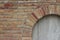 Beautiful antique brick wall texture sprinkled with hot pepper hued bricks of red, tan, pink and brown, with arched window