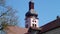 Beautiful antique pink church tower in baroque and rococo style with brown-red brick roofs in front of a blue sky without clouds,