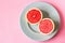 Beautiful appetizer fresh red grapefruit citrus fruit with half slice on blue plate and pink background close up top view natural