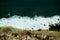 Beautiful aquamarine sea waves crash against black rocks