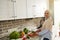 Beautiful Arab Muslim woman with covered head in hijab looks at camera while cutting ingredients and preparing vegetable salad in