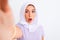 Beautiful arabian girl wearing hijab make selfie by camera over isolated white background scared in shock with a surprise face,