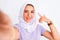 Beautiful arabian girl wearing hijab make selfie by camera over isolated white background very happy pointing with hand and finger