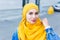 Beautiful Arabic muslim woman wearing yellow hijab, stylish female face portrait over city street.