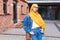 Beautiful Arabic muslim woman wearing yellow hijab, stylish female portrait over city street.