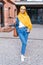 Beautiful Arabic muslim woman wearing yellow hijab, stylish female portrait over city street.