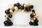 A beautiful arch of black and gold balloons, highlighted by sparkling gold balloons, gold and black balloon arch on a white