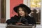 Beautiful aristocratic woman in black wide-brimmed hat and lace gloves, retro suitcase. Female traveler is waiting for train