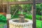 Beautiful artesian well made by stones and wheel pulley with metal bucket and rope in peaceful garden atmosphere. Retro stone