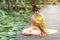 Beautiful asia women wearing traditional Thai dress and sitting on wooden bridge. Her hand is in the respect hands in thailand