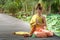 Beautiful asia women wearing traditional Thai dress and sitting on wooden bridge. Her hand is in the respect hands in thailand sty