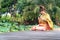 Beautiful asia women wearing traditional Thai dress and sitting on wooden bridge. Her hand is in the respect hands in thailand sty