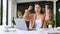 Beautiful Asian businesswoman celebrates at her office desk, looking at her laptop screen