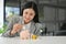 Beautiful Asian businesswoman insert coins in a pink piggy bank on the table