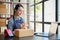 Beautiful Asian businesswoman working at her desk in her home office, listing her online orders