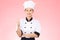 Beautiful Asian chef woman smile and make thumbs up good hand sign  on pink background