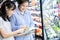 Beautiful asian daughter enjoy her mother while shopping in a food store,woman consumer reading product information, child girl