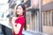 Beautiful Asian female in red dress stands holds a fan among old city center in Chinese new year theme