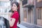 Beautiful Asian female in red dress stands holds a fan among old city center in Chinese new year theme