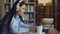 Beautiful asian female student in headphones sitting at desk in library working concentrated at school project. Young