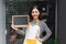 Beautiful asian florist holding blank sign and pointing at copy space.