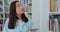 Beautiful asian girl in blue shirt walks along the shelves with books in the library. College education concept.