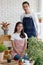 Beautiful Asian girl man ware jean and pink apron sit and stand together looking at camera in white room surround by trees