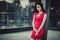 Beautiful Asian girl model in red dress posing at the modern glass style city background.