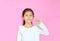 Beautiful asian little girl showing pinkie finger isolated on pink background. Portrait of smiling kid expression little fingers