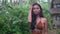 Beautiful asian model in brown knitted top stands on tropical path near cottage