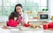 Beautiful Asian mother and mixed race adorable little daughter sitting in kitchen, drawing, painting, doing homework or activities