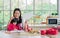 Beautiful Asian mother and mixed race adorable little daughter sitting in kitchen, drawing, painting, doing homework or activities