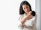 Beautiful Asian mother talk to her newborn baby in front of white curtain with day light